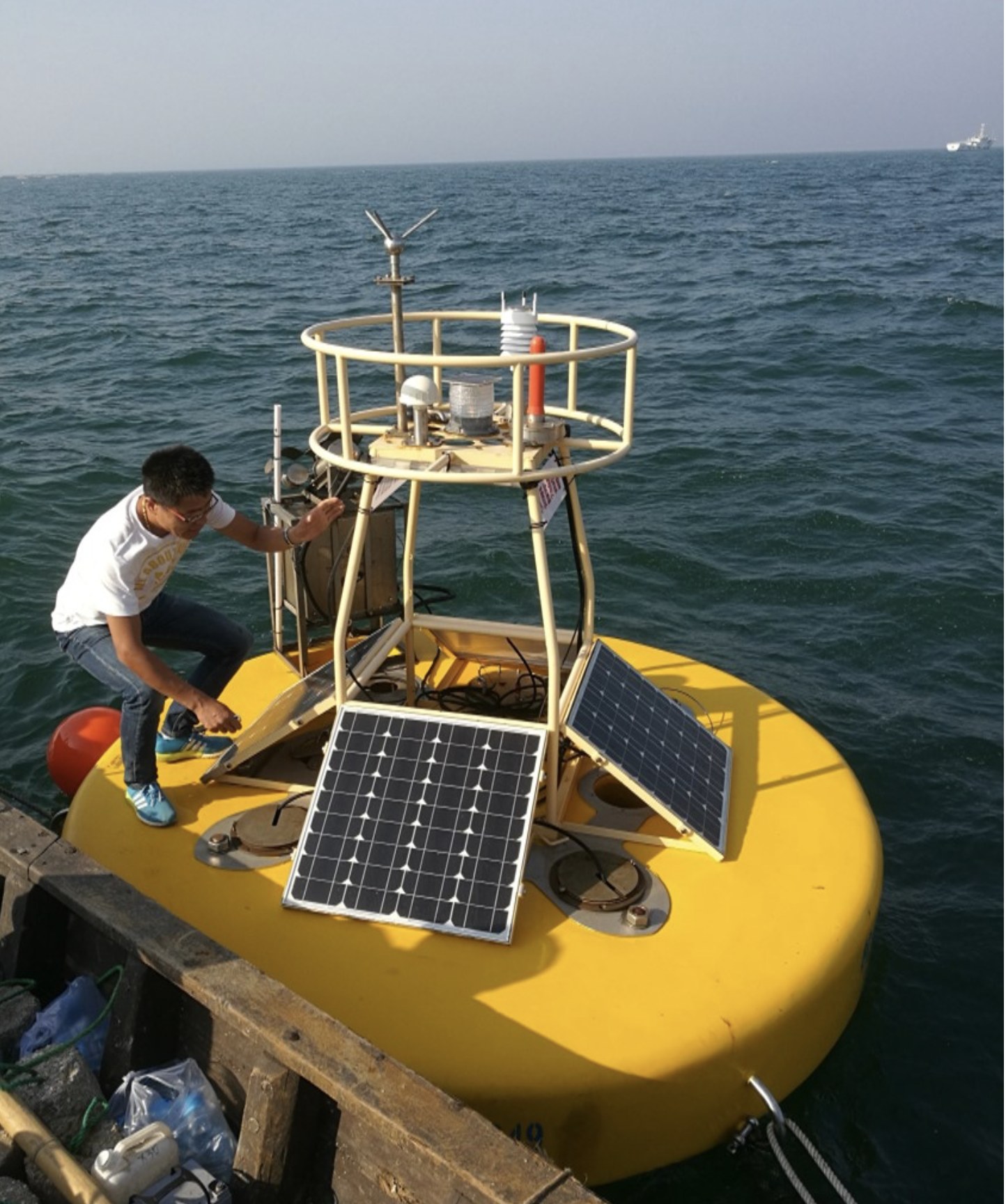 Technician servicing a solar-powered research buoy at sea